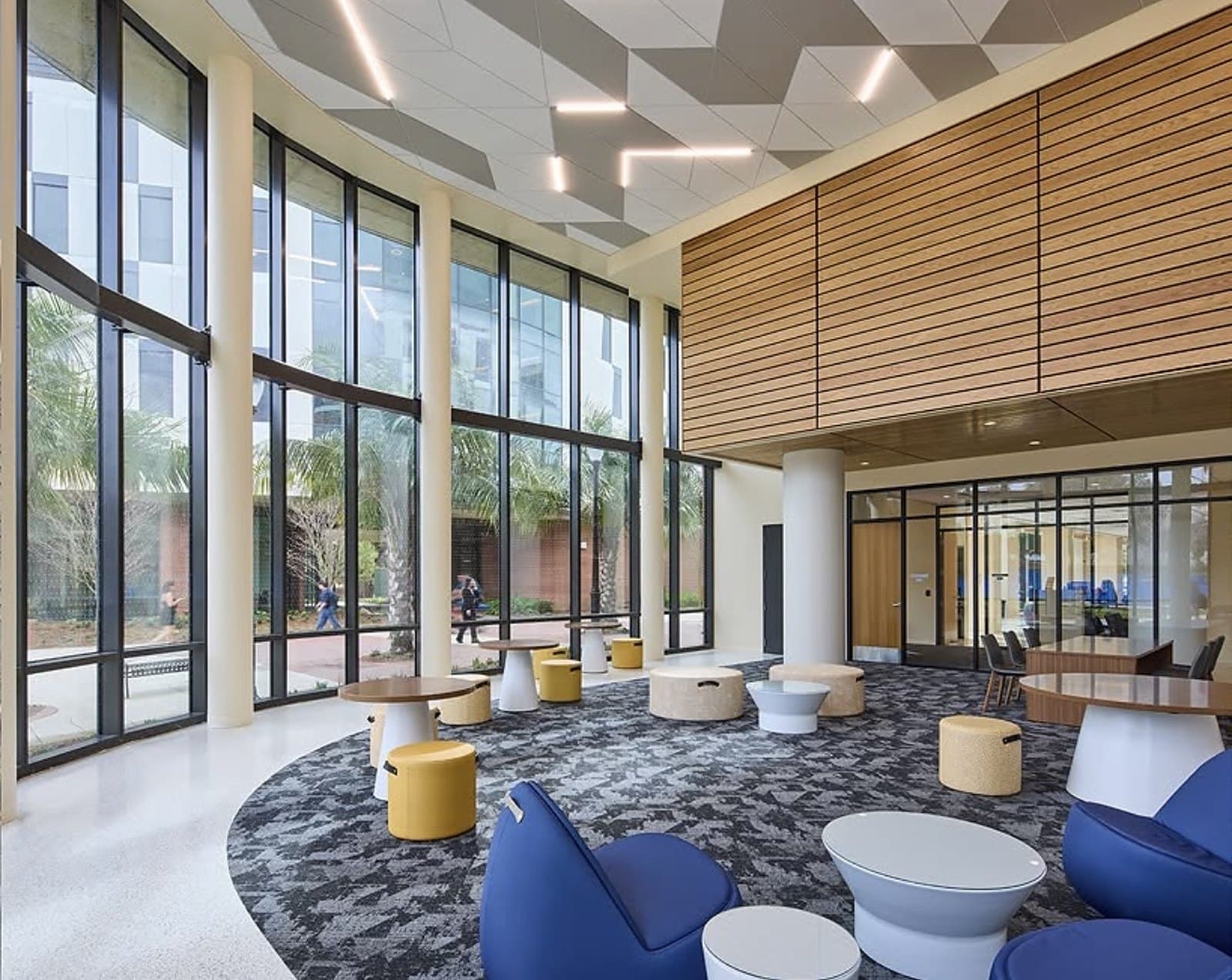 UF Honors Village — double-height commons lounge with motorized roller shades on the full-height glazing