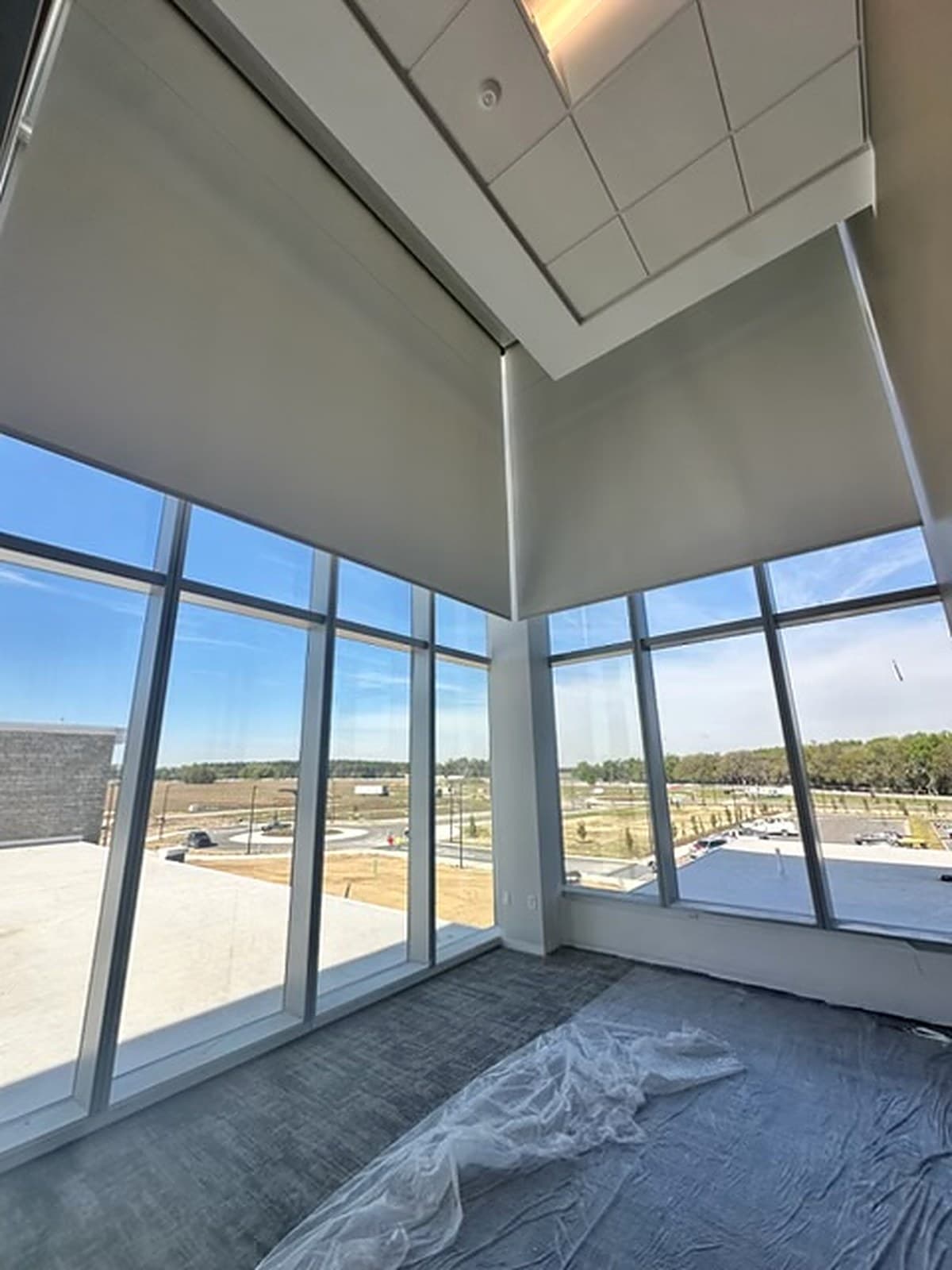 Tower Hill Insurance HQ — the same double-height corner with the motorized shades raised, full-height glazing and grounds beyond